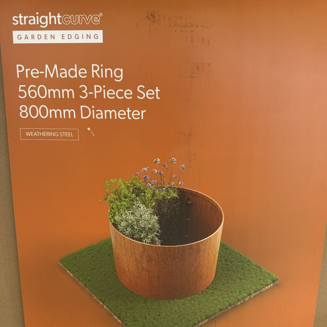 straight curve garden edging with a pot and grass on an orange background